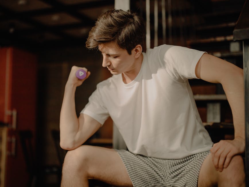 A young man performs a bicep curl with a dumbbell in a cozy home setting, focusing on fitness at home.