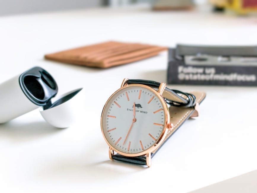 Minimalist wristwatch with leather strap on white table, showcasing sleek design.