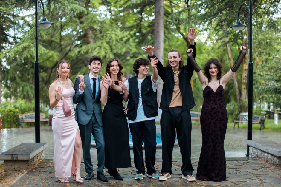 A diverse group of young adults celebrating outdoors in formal attire.