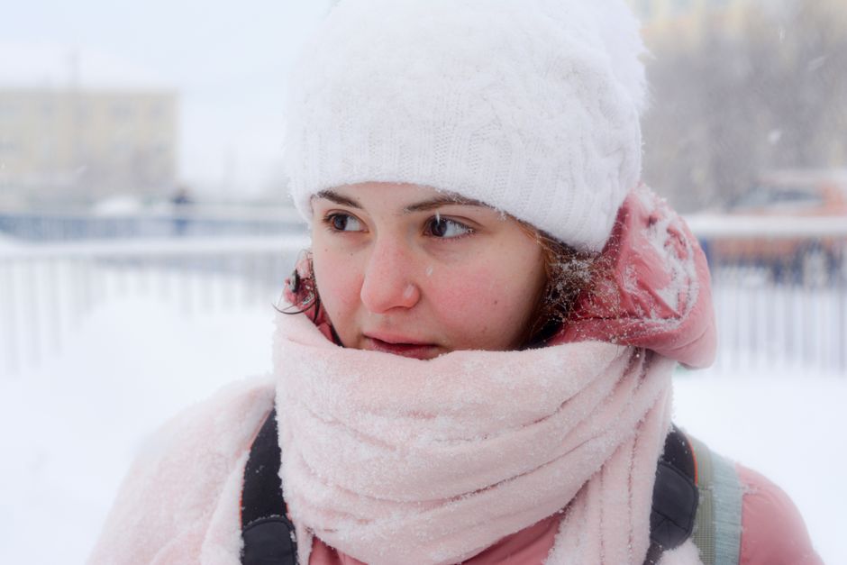 Close-up of a woman in winter clothing outdoors amidst snow. Captures the essence of winter fashion and cold weather.