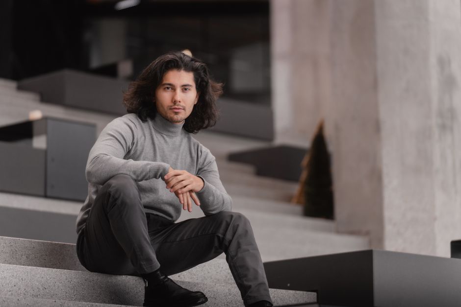 Fashionable man sitting on steps in a modern urban environment, showcasing elegance.