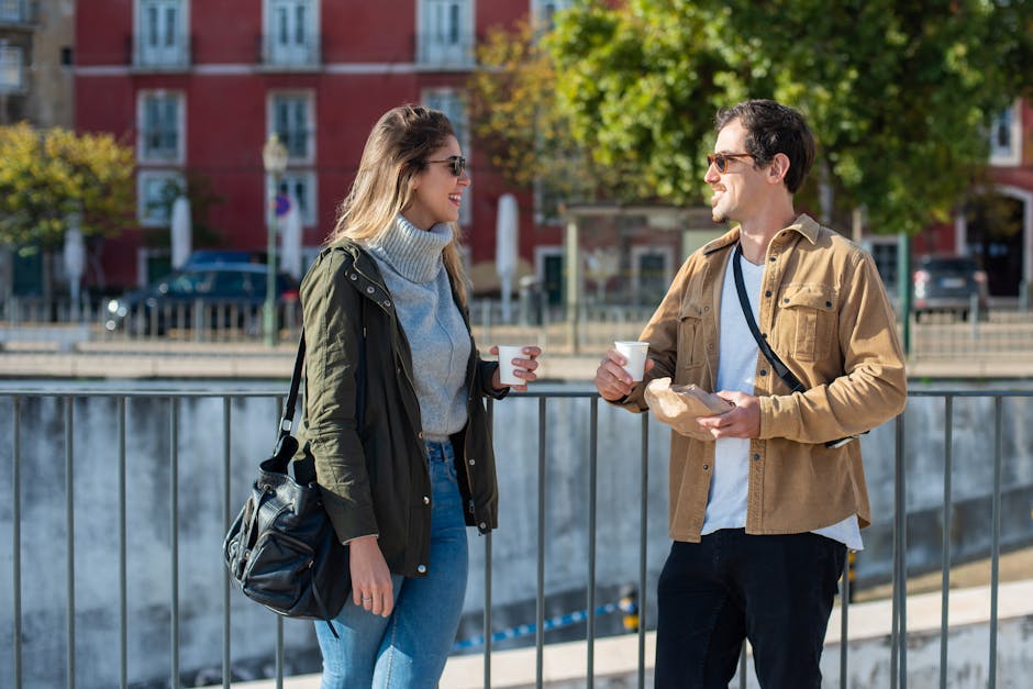 Smiling man and woman enjoying coffee outdoors on a sunny day.