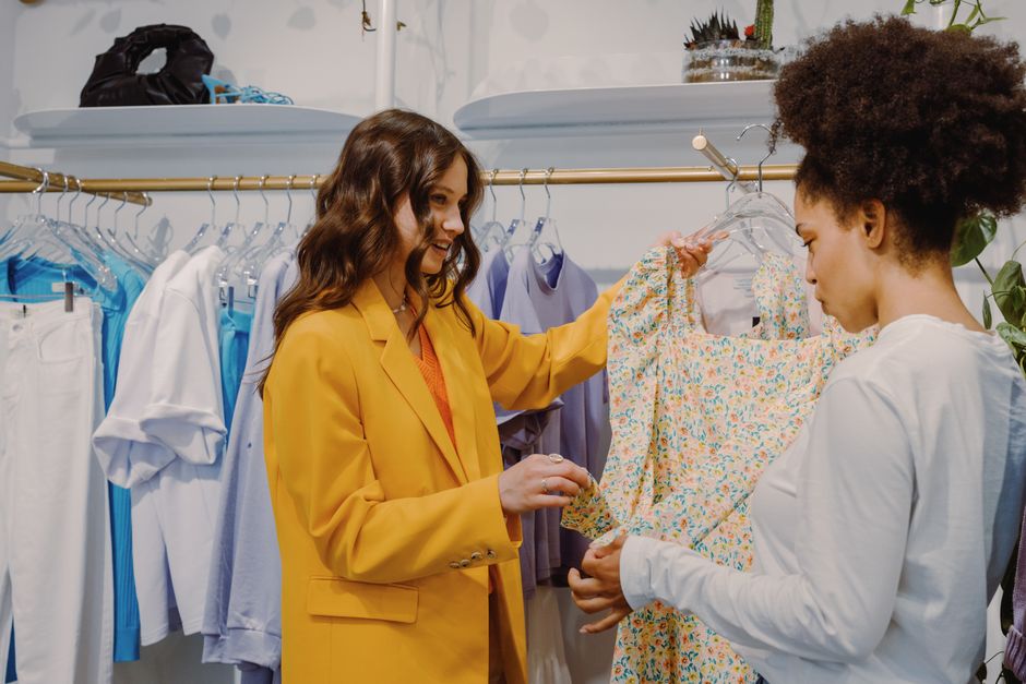 Two women engaging in a stylish clothing store, discussing fashion choices.