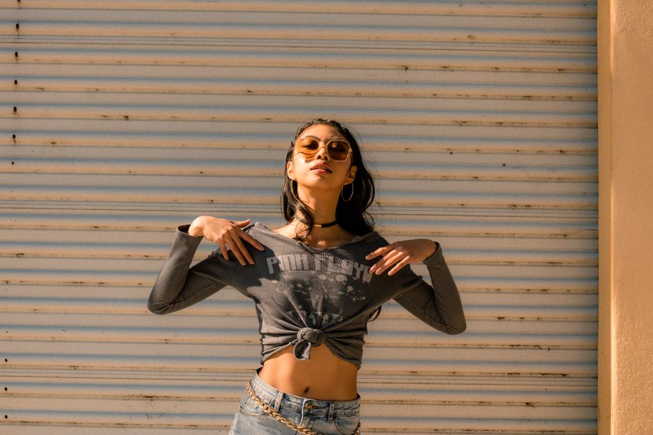 Fashionable woman in trendy outfit posing under sunlight with a bold expression.