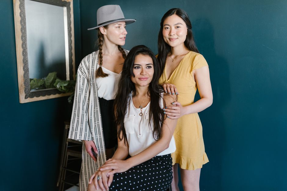 Three diverse women posed together indoors, highlighting friendship and elegance.