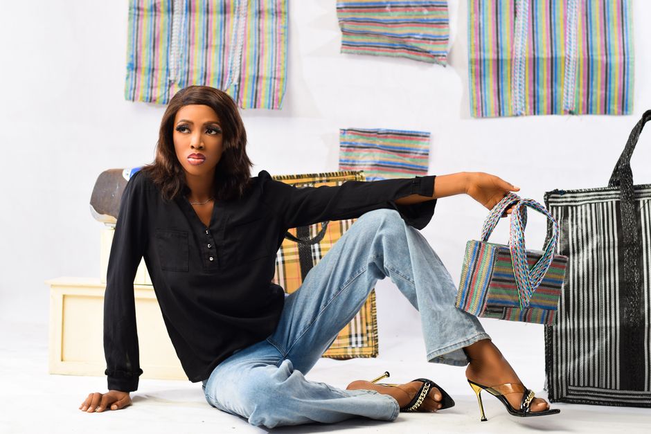 Fashion model in a studio shoot wearing black blouse and jeans, holding a stylish bag.