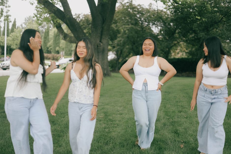Four friends laughing and enjoying a sunny day in a park.