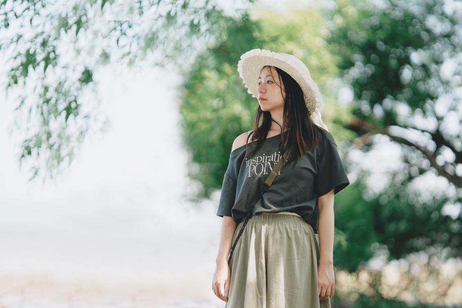 A serene outdoor portrait of a woman wearing a sunhat, surrounded by lush greenery.