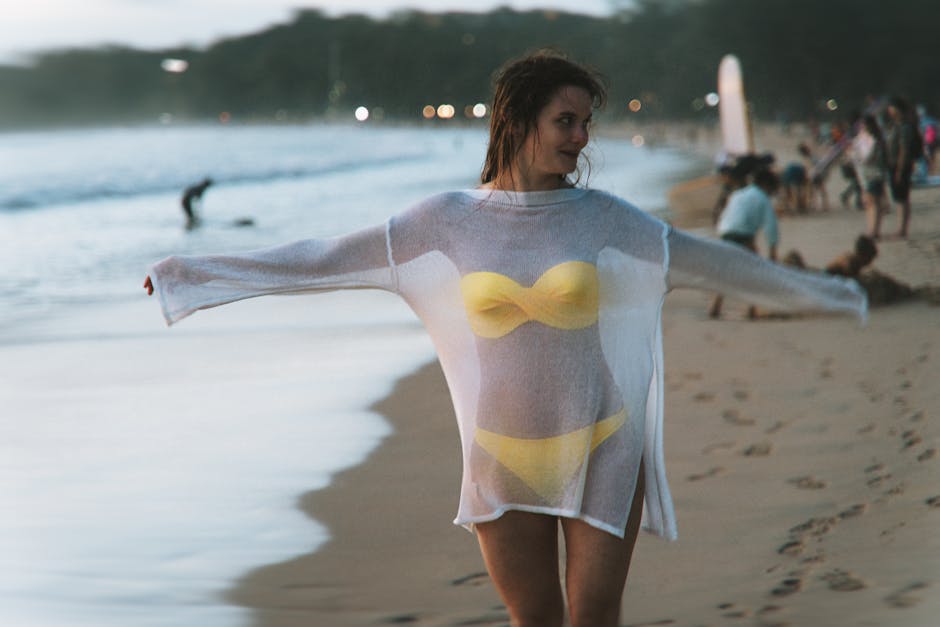 A woman in a yellow bikini and sheer cover-up enjoying Phuket beach during sunset.