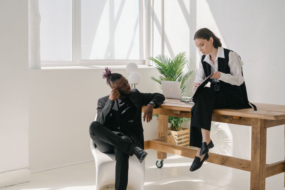 Two professionals discuss work at a sunlit office, fostering collaboration.