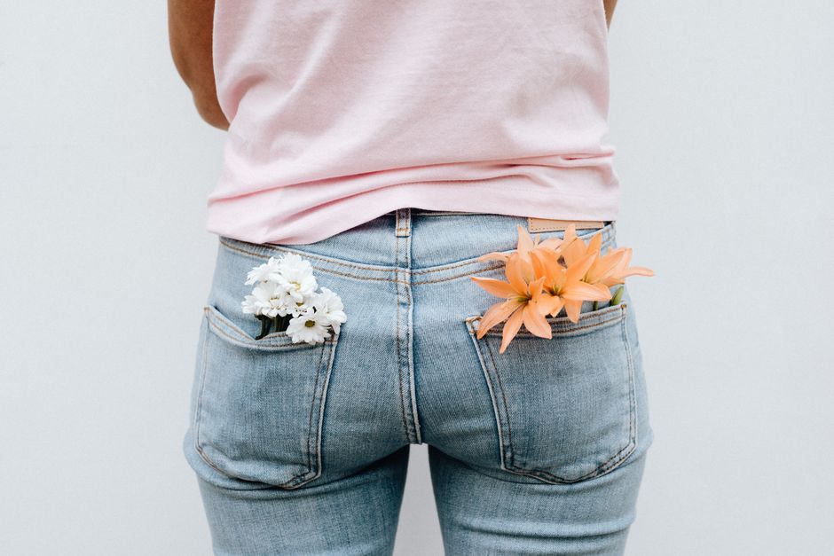 Back view of a person in jeans with flowers in pockets, creating a unique fashion statement.