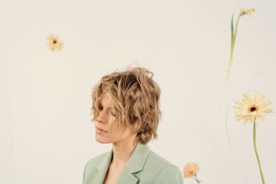 A serene portrait of a woman with short hair and a floral background, evoking a calm and elegant mood.