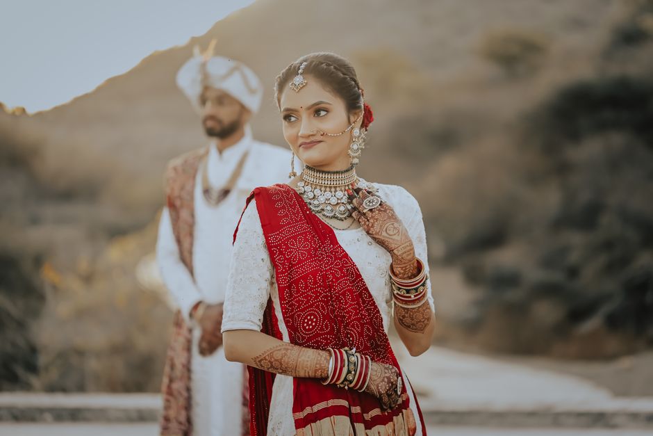 Traditional Indian couple in elegant attire, captured during an outdoor wedding ceremony with beautiful henna and jewelry.