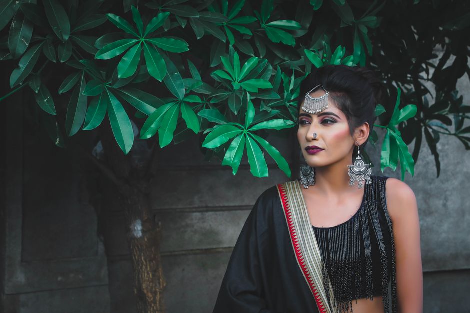 Elegant Indian woman in traditional attire and jewelry, standing outdoors.