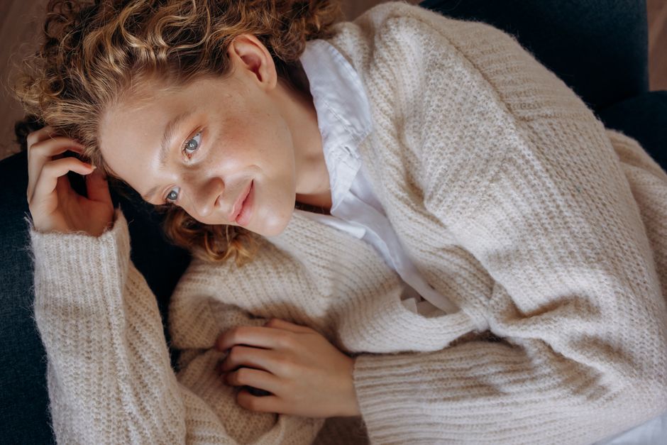 Portrait of a relaxed woman lounging in a cozy knitted sweater, looking serene and comfortable indoors.