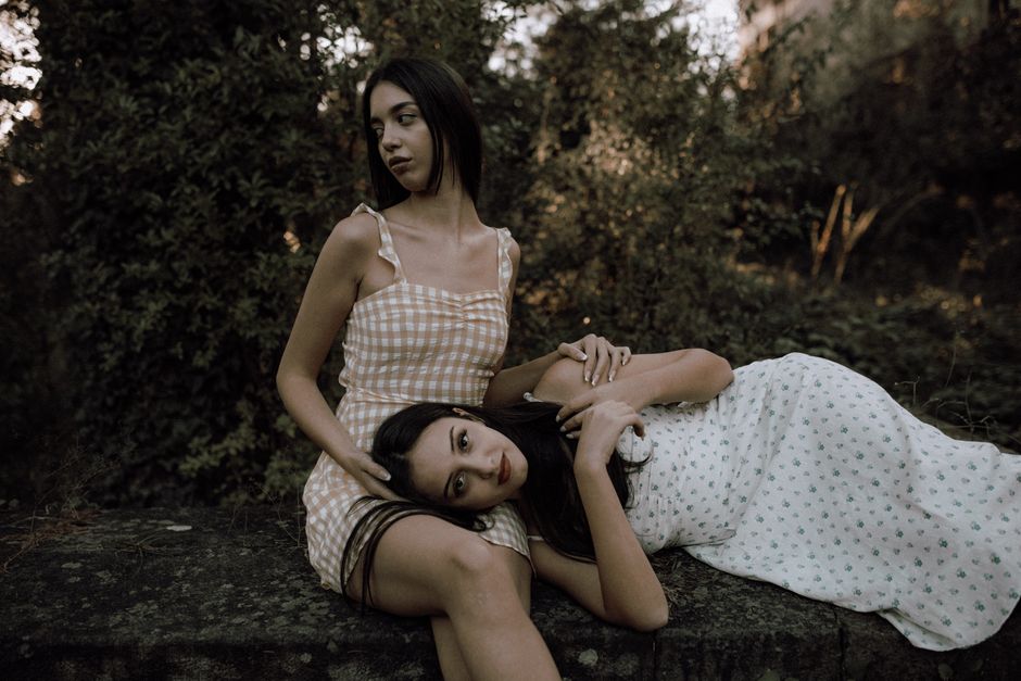 Two young women pose elegantly outdoors, capturing a serene and artistic moment in nature.