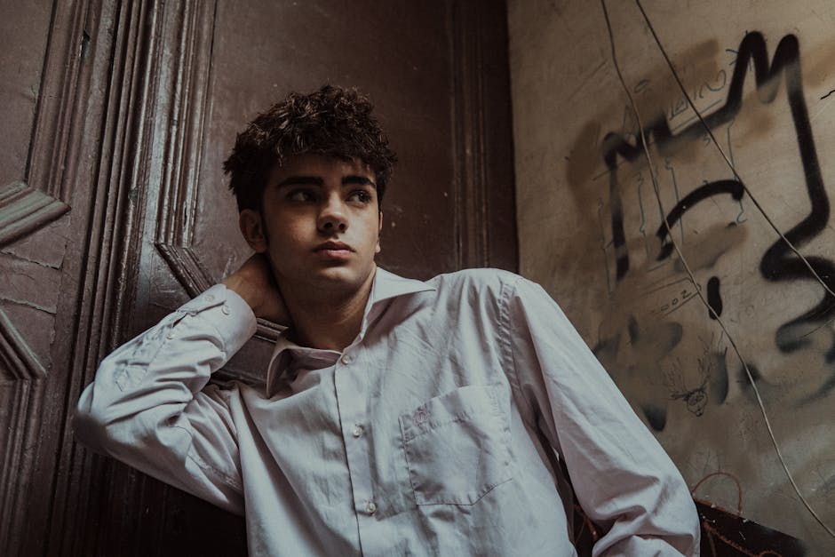 Portrait of a young man leaning against a graffiti-covered wall in Istanbul, exuding a pensive mood.