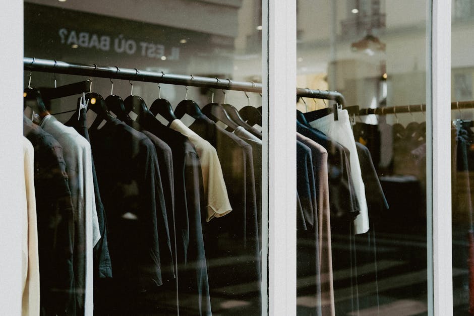 Close-up of clothing on hangers inside a fashion store window.