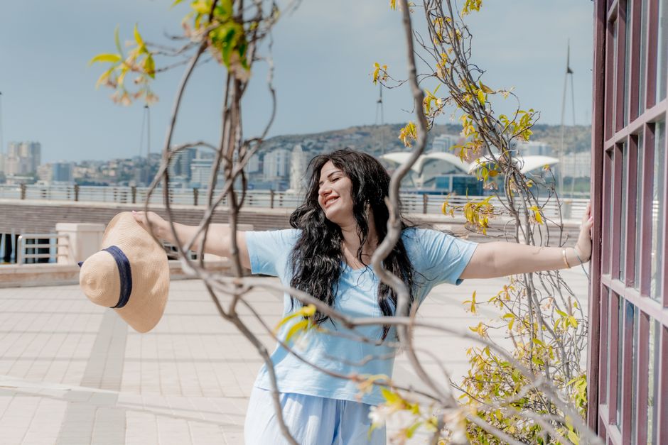 A woman enjoys a sunny day at the Baku waterfront, embracing freedom and relaxation.