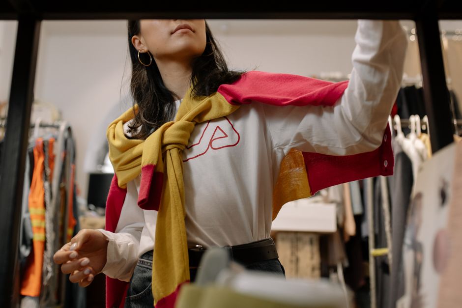 A stylish woman browsing clothes in a trendy fashion store with a modern, chic feel.