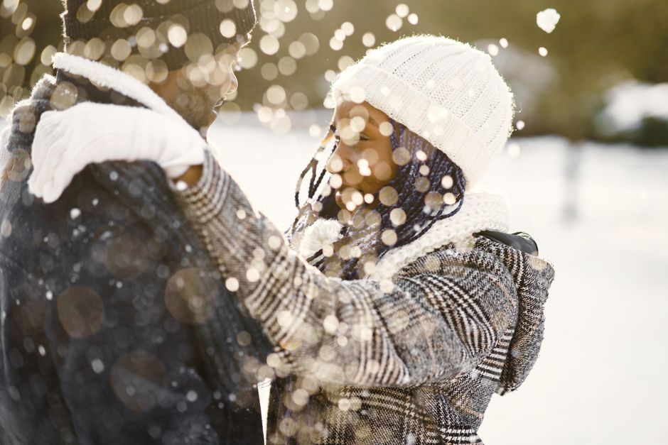 Couple enjoying a romantic moment in the snow, sharing warmth with a loving embrace.